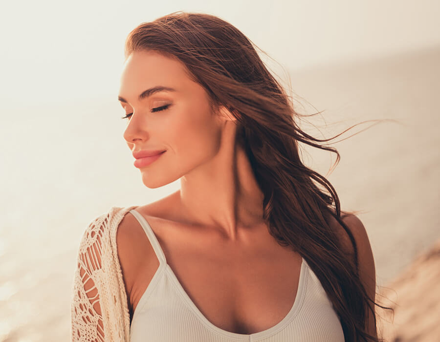 Woman at the beach smiling with her eyes closed